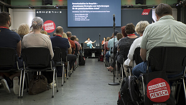Foto einer Rede auf der EUREF-Konferenz 2023, Blick zwischen den Sitzreihen hindurch zum Podium.