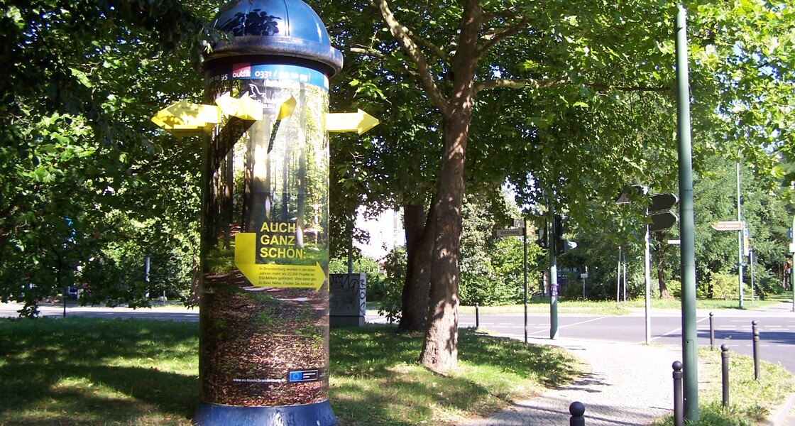 Litfaßsäule mit angeklebten gelben Pfeilen