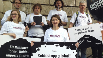 A group of people with demo posters and giant balloons in their hands.